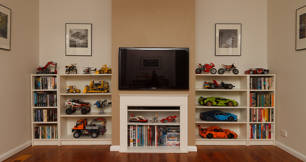 End wall of my lounge, 40" television mounted in the centre, shelves with lego and books on either side